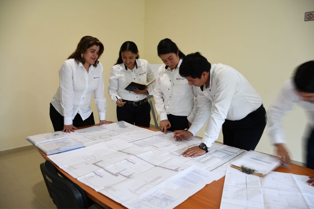 Equipo de prtofesionales de Rialvas analizando unos planos estructurales dentro de una oficina sobre una mesa grande.