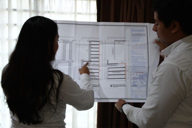 Dos ingenierops, una mujer y hombre analizando un plano estructural
